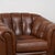 Pair of English club chairs upholstered in vintage brown leather. Each chair features a tufted button back, rolled arms,...