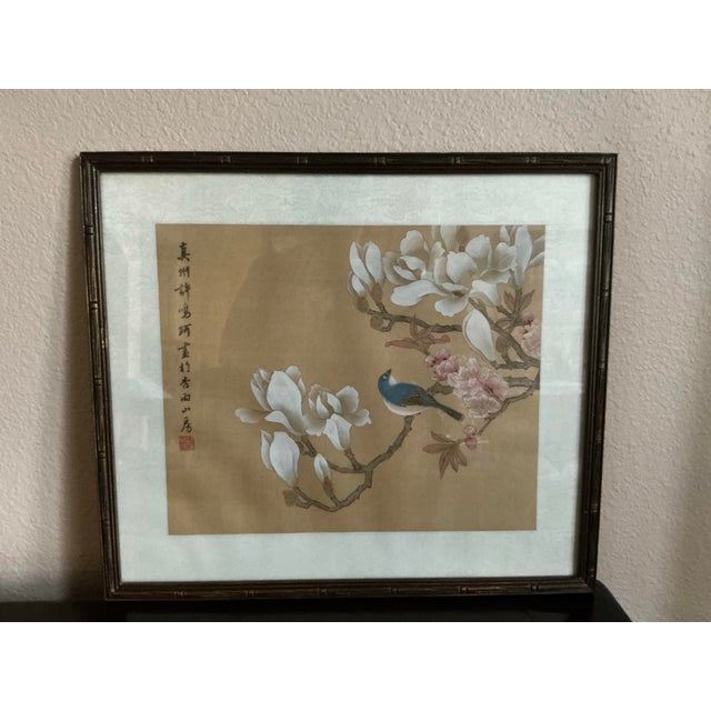 Vintage framed East Asian botanical painting featuring a blue songbird perched on a flowering branch with large white...