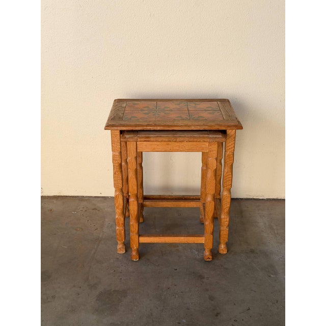 Charming set of vintage Danish nesting tables crafted in solid oak, featuring decorative ceramic tile inlays on the tops....