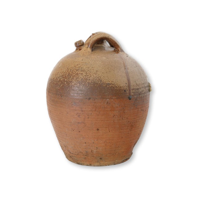 Late 19th century French glazed terracotta jug with classic provincial form and double handles arching from the shoulder...