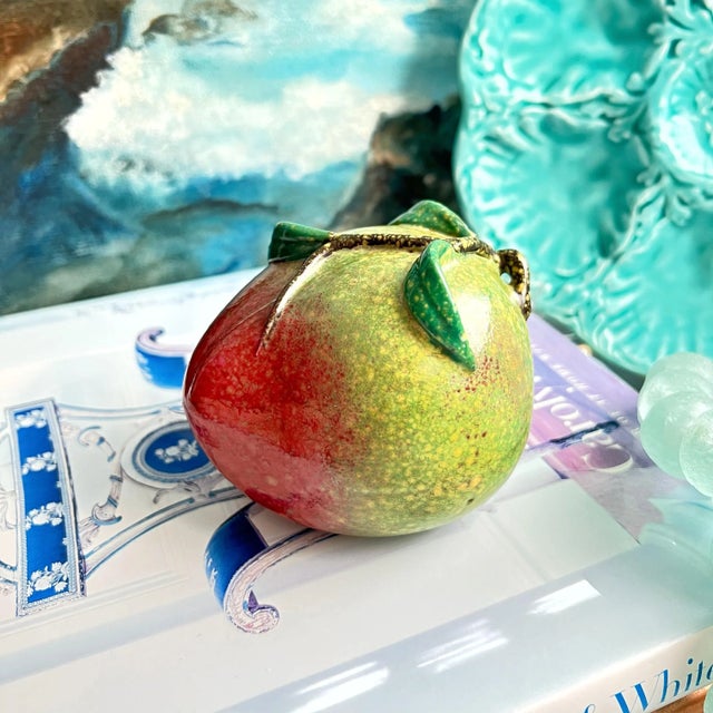 A piece of ceramic altar fruit in the shape of a peach with applied stem and leaves. Circa Late 20th Century.
