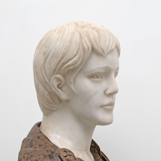 A refined polychrome marble sculptural bust depicting a young Roman emperor, crafted with meticulous attention to detail...
