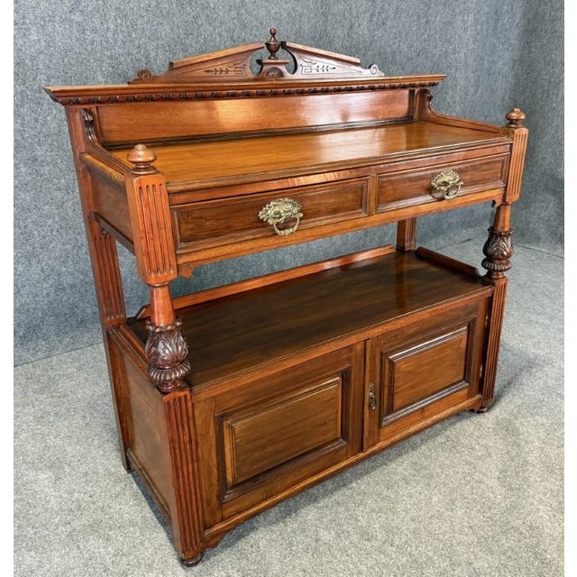 This 19th century solid walnut two-tier server showcases finely carved details, fluted columns, and a decorative crest...
