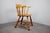 A distinctive vintage Windsor-style armchair dating to approximately the 1970s–1980s, featuring a warm honey-toned wooden...