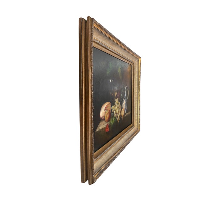 A beautiful chunky antique gold framed still life oil painting of fruit, wine, and pottery. The blue-and-white pottery...