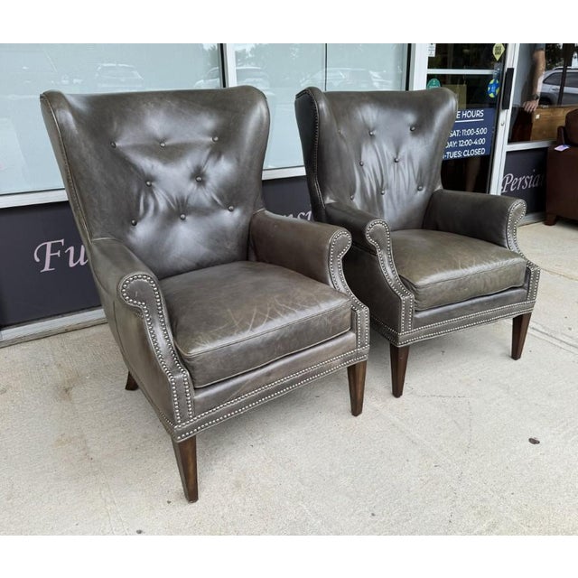 This pair of Hooker Furniture Maya chairs features gently flared wingbacks, button tufting, rolled arms, and nailhead...