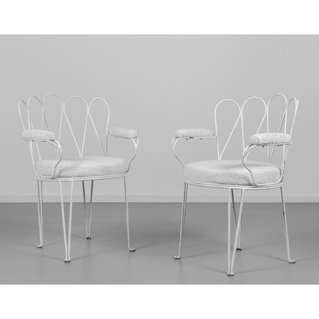 Two armchairs in steel rod, painted white, with cushions and armrests covered in fabric This piece is attributed to the...
