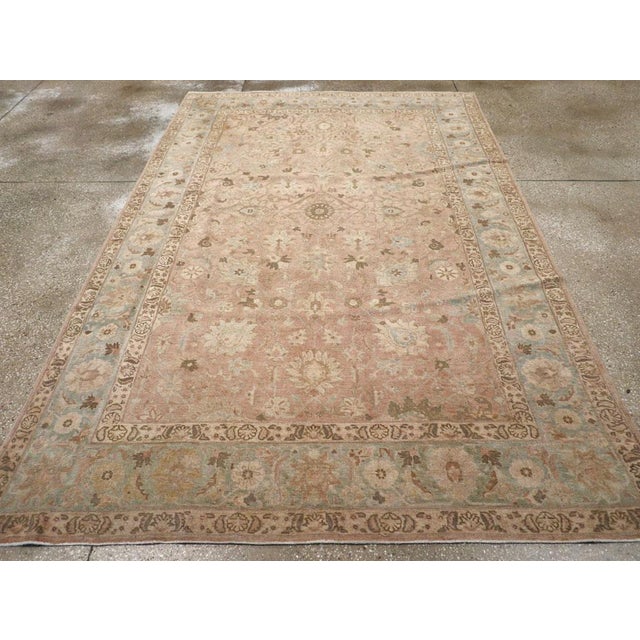 This early 20th-century Persian Tabriz accent carpet presents a softly balanced floral composition across a warm salmon...