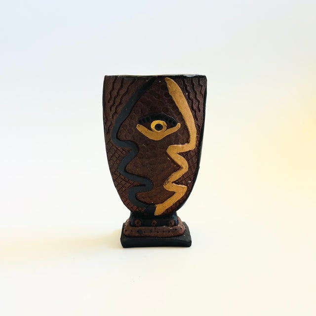 A vintage art pottery vase. Unique tapered oval shape with a pedestal shape. Features an applied design to a textured...