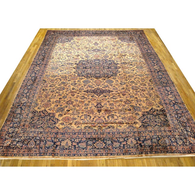 An antique Indo-Kashan oriental carpet, size 22'4 H x 16'0 W, circa 1920. This massive hand-knotted wool carpet features a...