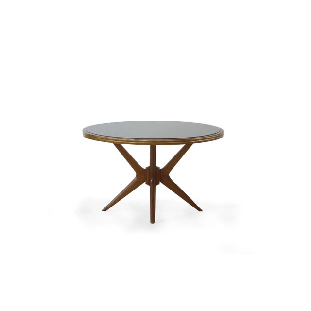 This table features four oak legs, supporting a round top with encased black glass and a brass edge.