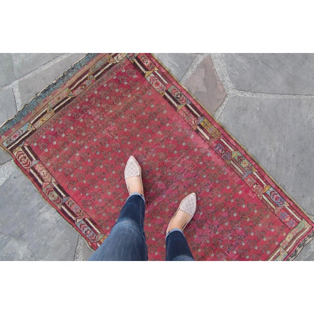 This small antique piece is a marvelously hand-knotted treasure of time. The small blue flowers make up the allover...