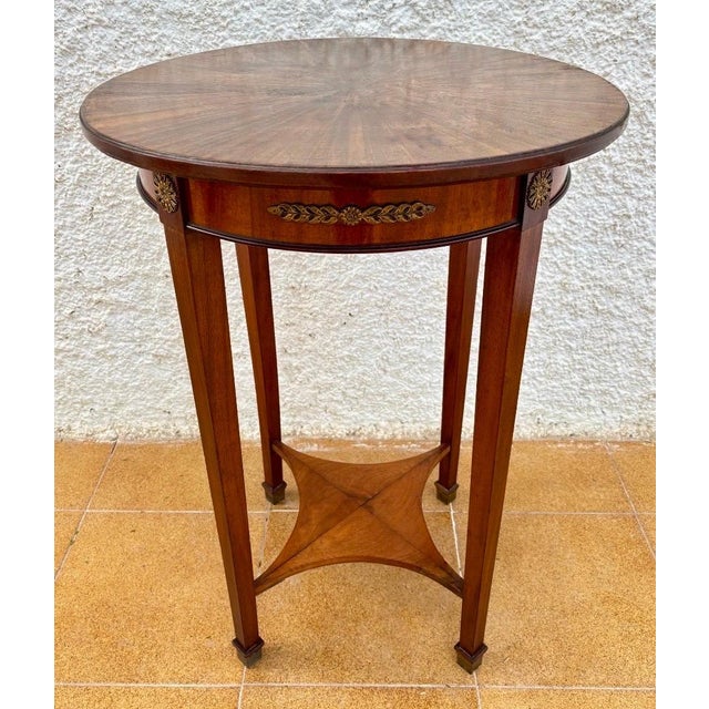 Elegant French Neoclassical side table dating from the 20th century, featuring a round sunburst veneer top and refined...