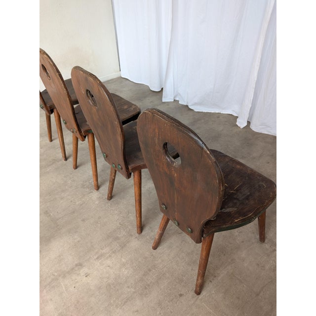 Vintage wooden dining chairs made in Yugoslavia, circa 1960s–1970s. The chairs feature a charming rustic folk design with...