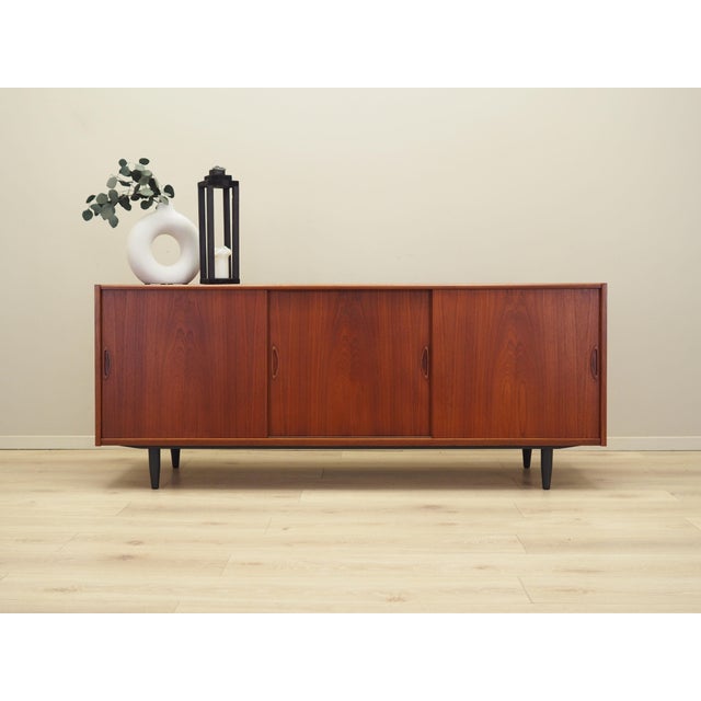 The sideboard was made in the 1970s, Danish production. The structure is covered with teak veneer. The legs are made of...
