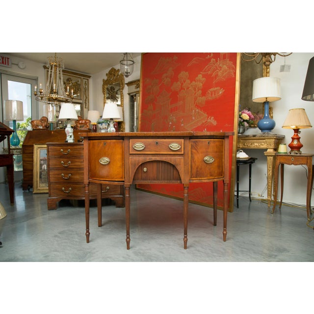 This is a small, but sophisticated American Federal inlaid mahogany bow front breakfront sideboard. The top has a straight...