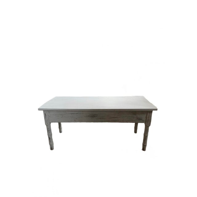 This is a traditional wooden coffee table from the early 21st century. The color is white with a little distressing.