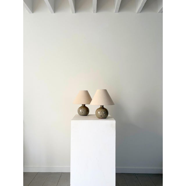 A charming pair of petite 20th century ceramic lamps. These mid century french studio pottery pieces have a spherical...