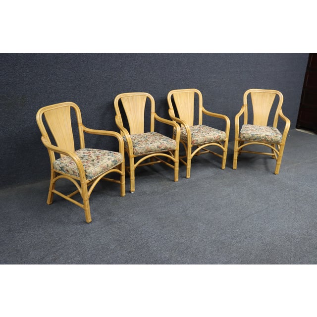 Set of four MCM-style bamboo and rattan fan back armchairs featuring sculptural curved arms, wrapped rattan detailing, and...