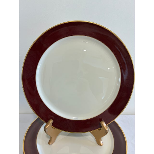 A refined set of 8 vintage finds Pickard Fine China dinner plates, each featuring a rich, solid burgundy band bordered in...