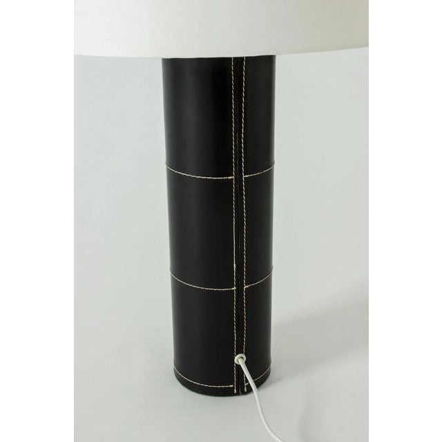 Large table lamp from Bergboms with a cylinder base dressed in black leather. Decorated with white seams – a minimalist...