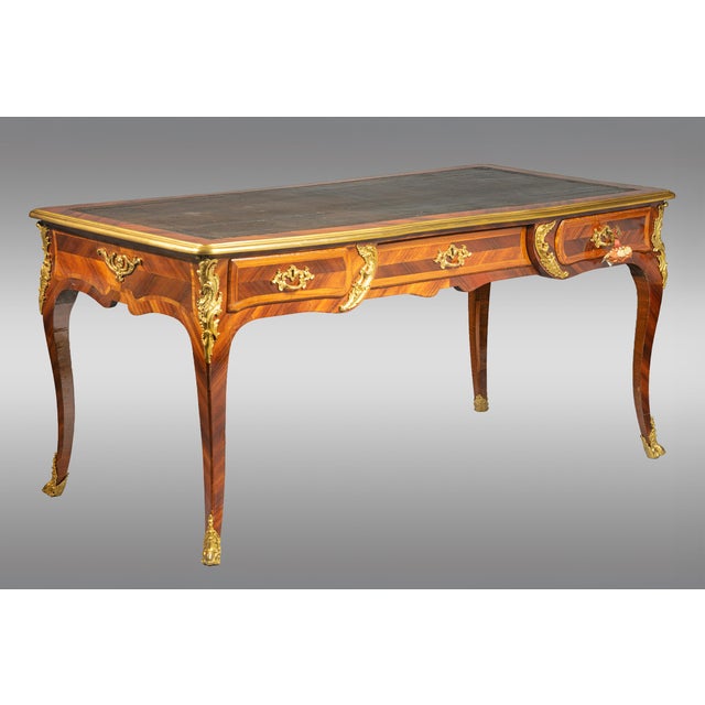 An eighteenth-century Louis XV flat desk , with oak interiors and gilt bronze mounts. The original green leather top. It...