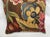 An exquisite antique-style pillow upholstered in richly woven 19th-century tapestry, set against a deep warm brown ground...