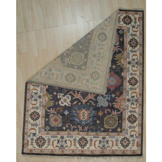 This blue hand knotted pile rug is crafted from wool and originates from India. It features a distinct Oushak style that...