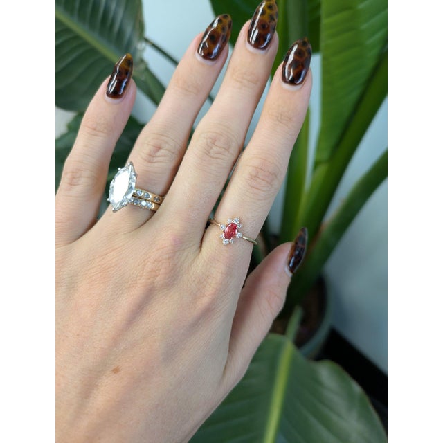 A 0.69-carat padparadscha sapphire oval sits at the centre of this solid 14K yellow gold ring, framed by eight earth-mined...