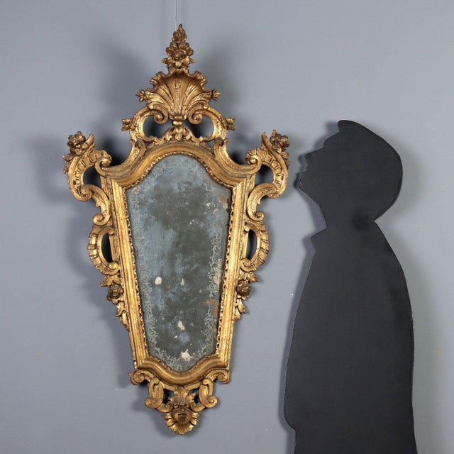 Carved and gilded wood mirror from late 18th century Italy, distinguished by an elegant frame decorated with floral,...