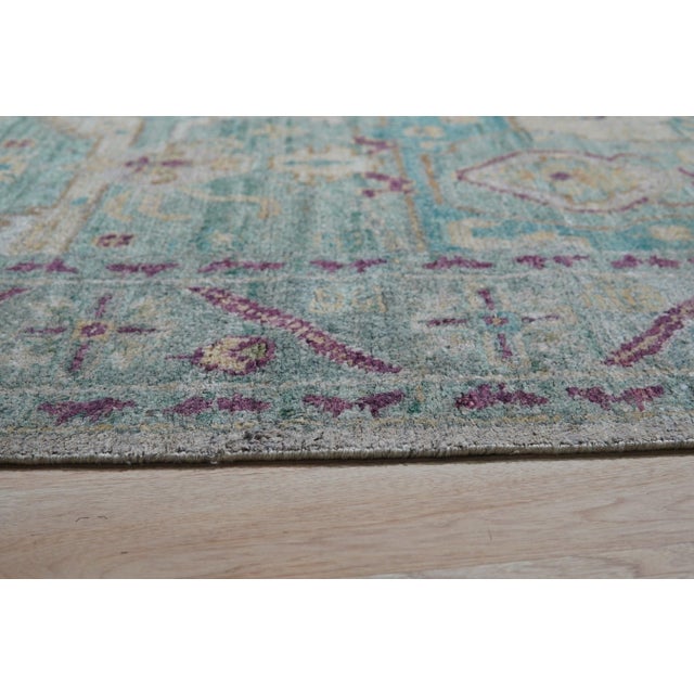 A hand-knotted silk rug, made in India and measuring 8' x 10'. Floral drawing carried across the field inside a...