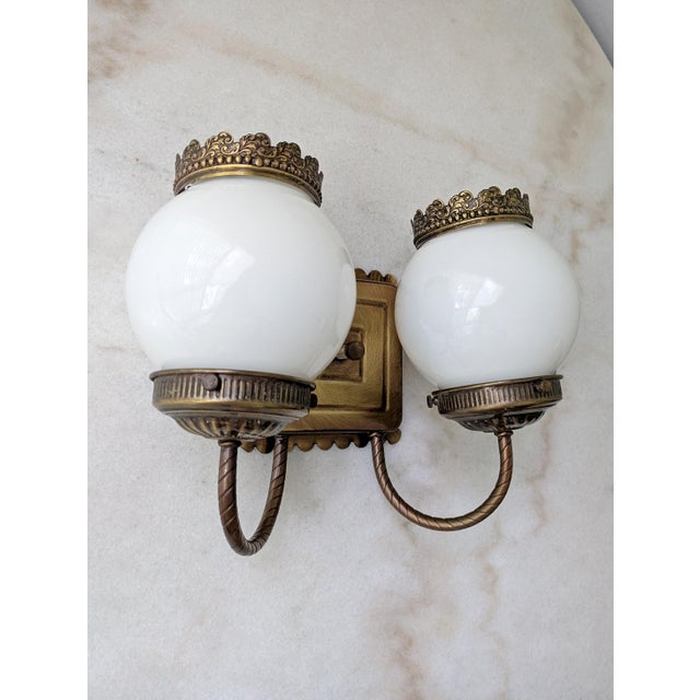 Vintage electric wall sconce featuring an elgeant aged brass scalloped edge backplate and charming milk glass shades.