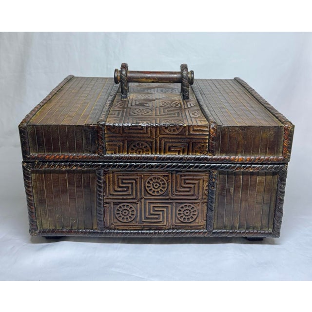 Vintage Chinese wood box. Exterior adorned with bamboo strips, coiled rattan borders, and wood top handle. Embossed...