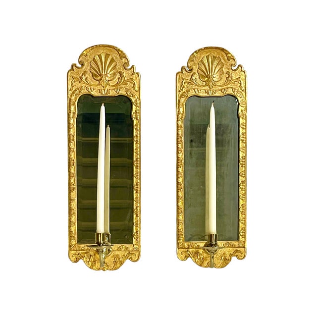 Elegant pair of Rococo-style wall sconces featuring richly carved giltwood frames with shaped crest details and antiqued...