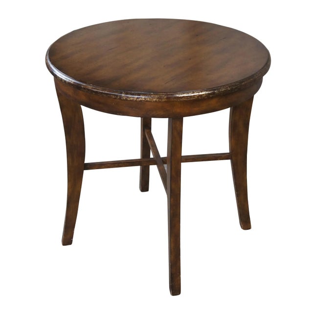 Vintage mahogany finished center or accent table featuring round form with an antiqued rubbed gold paint edge over four...