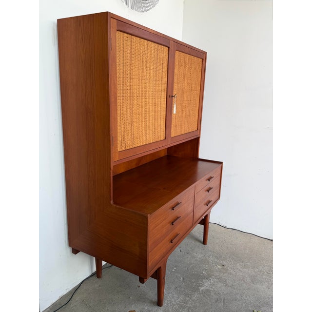 A mid century Danish modern storage hutch. The case is executed in teak and raised on tapered legs. The upper cabinet...