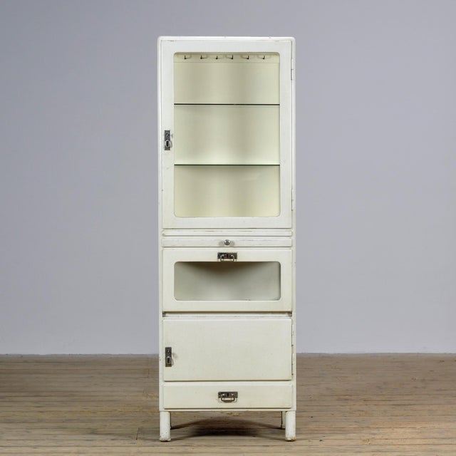 This wooden medicine cabinet from the 1930s combines functionality with timeless charm. The upper section features two...