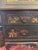 Drop front black chinoiserie desk. Gilded chinoiserie figures. 3 bottom drawers, 3 small desk drawers and cubbies behind...