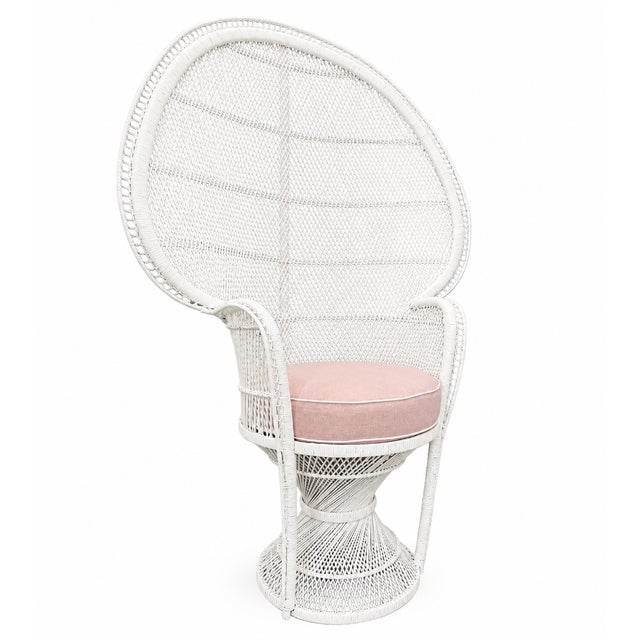 A striking vintage peacock chair featuring an elegant white lacquered wicker frame and a soft blush pink cushion. The...
