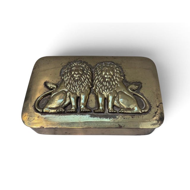 Gold toned metal box with relief of lions on the lid.