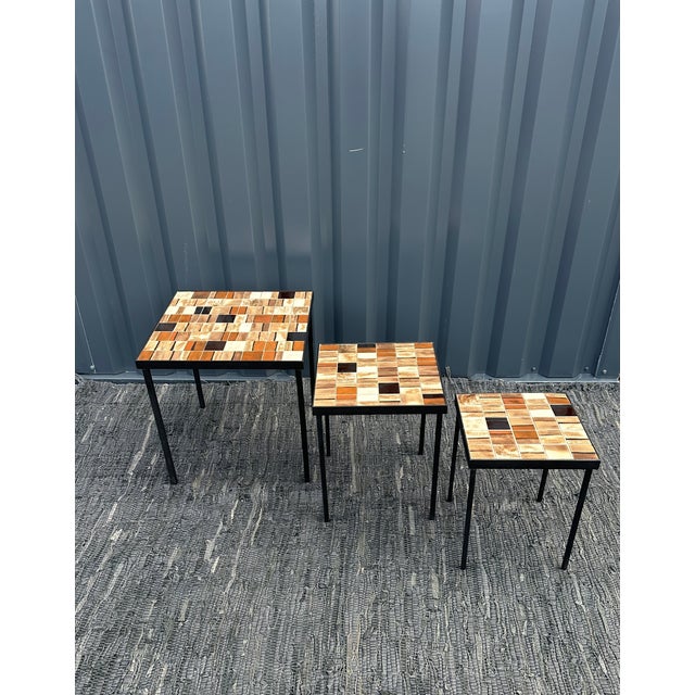 A set of three nesting coffee tables in different sizes, covered in ceramic tiles by the renowned ceramicist Mado Jolain....