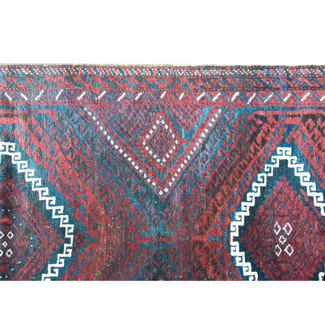 A wonderful mid-20th century Afghani Baluch rug with three large diamond medallions with stylized scrolling vine patterns...