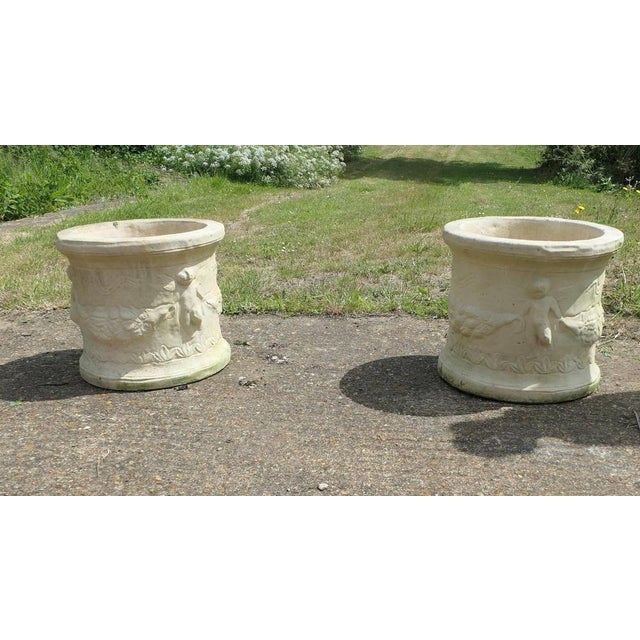 A Pair of Round Garden Planters with Winged Cherubs This is a good large pair, the planters are round and they have...
