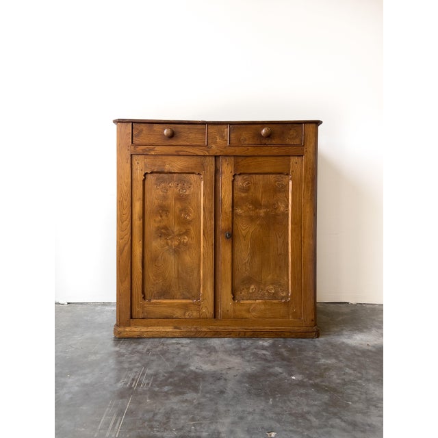 An antique late 19th century French elm cupboard with beautiful wood grain and a warm patina. Two drawers with wooden...