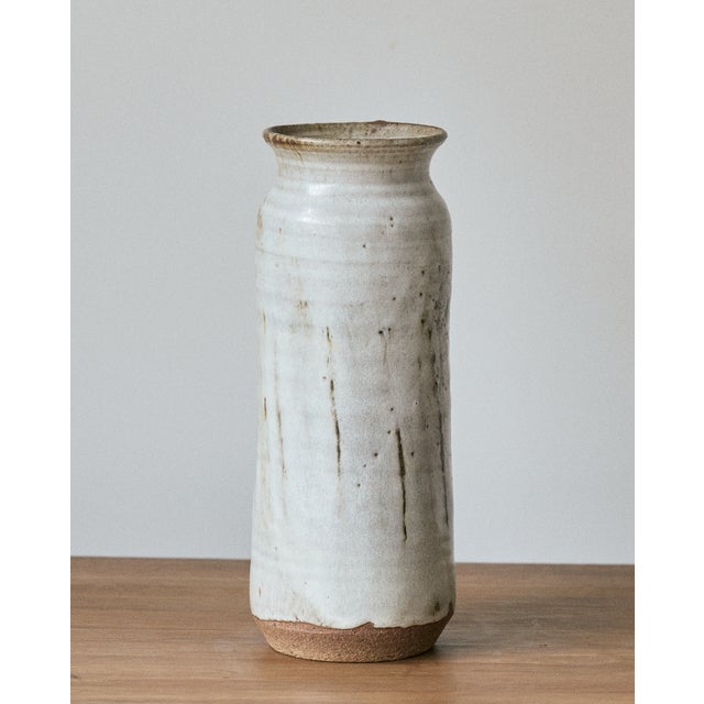 Tall ceramic studio art vase with an earthy, speckled white glaze and an exposed raw clay base. This vintage vase is...