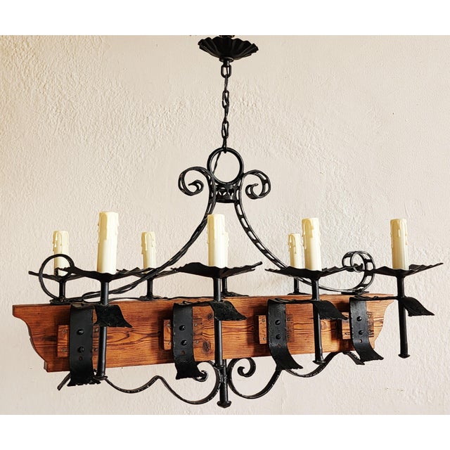 Vintage Spanish Revival hand crafted and hand forged wrought iron chandelier with center wood beam. The chandelier...