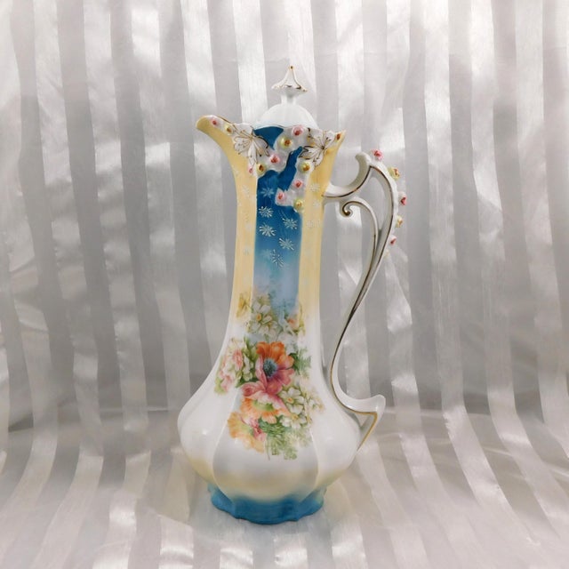 This is a white, pale yellow and teal blue Reinhold Schlegelmilch (RS Prussia) chocolate pot with a pink and yellow flower...