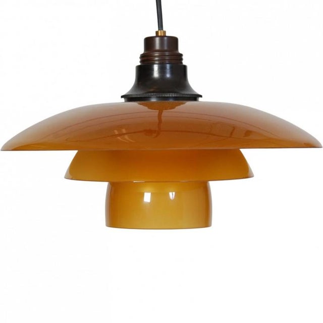 Poul Henningsen PH 3,5/3 pendant lamp with a bakelite fitting and amber colored opal glass shades. The lamp is from the...
