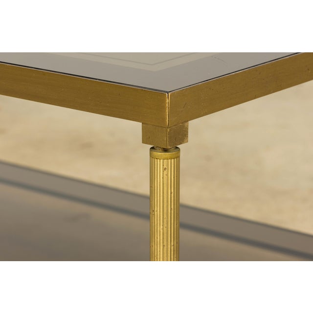 An elegant mid-20th century French Neoclassical coffee table, sourced in Provence, France. The table features a warm brass...