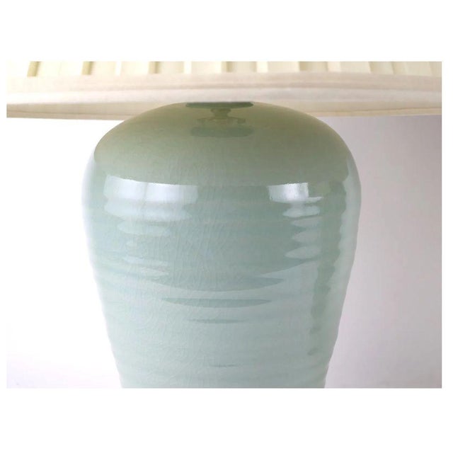 A pair of porcelain table lamps featuring softly tapered vase form bodies in a serene pale blue glaze with a crackle...